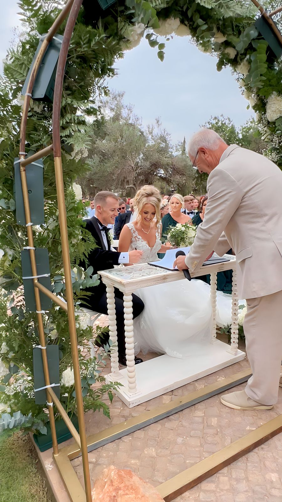 Couple signing the register under a floral arch